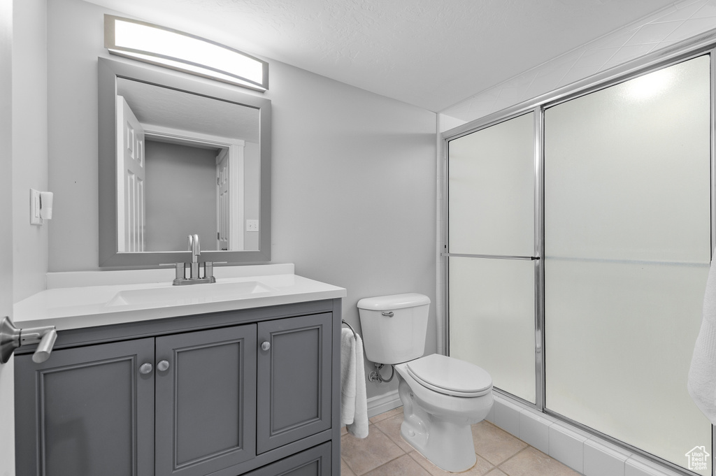 Full bath with vanity, a shower stall, toilet, and tile patterned flooring