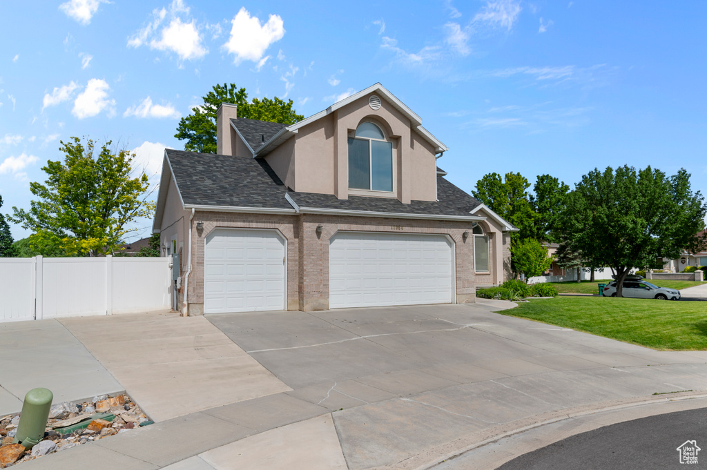 Traditional home with concrete driveway, stucco siding, a garage, roof with shingles, and a chimney