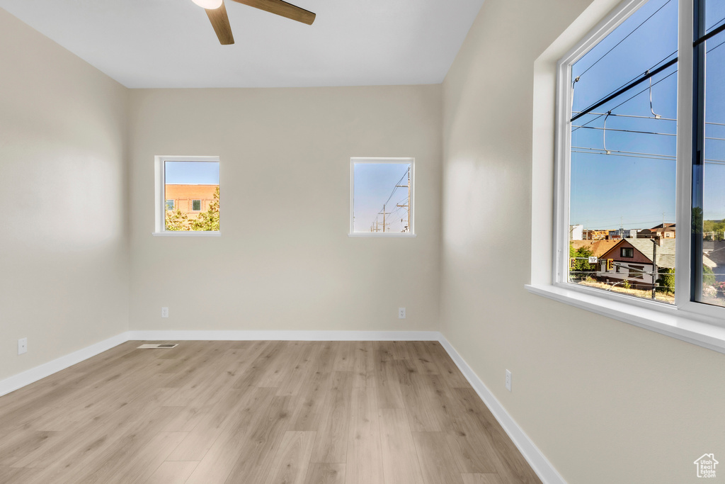 Unfurnished room featuring ceiling fan, light wood-style floors, and baseboards
