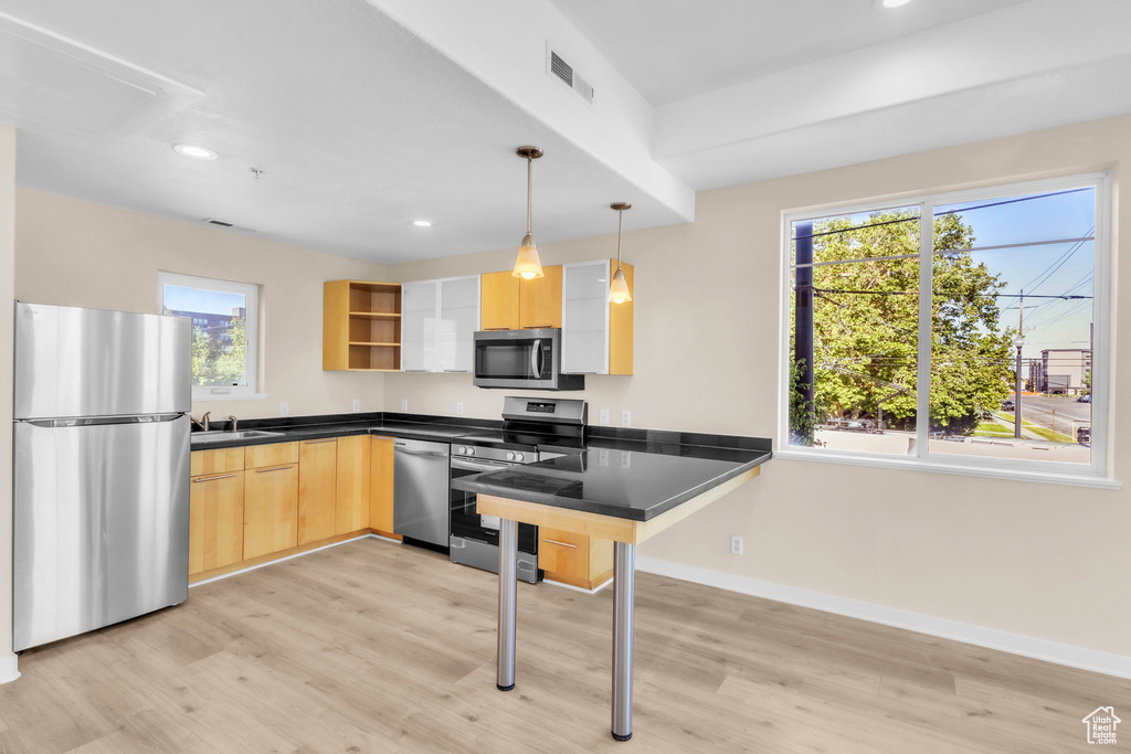 Kitchen featuring appliances with stainless steel finishes, light brown cabinetry, open shelves, light wood-style floors, and recessed lighting