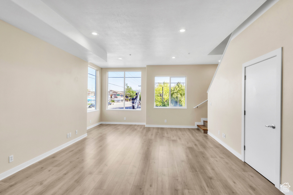 Unfurnished living room with stairs, light wood-style floors, recessed lighting, and baseboards