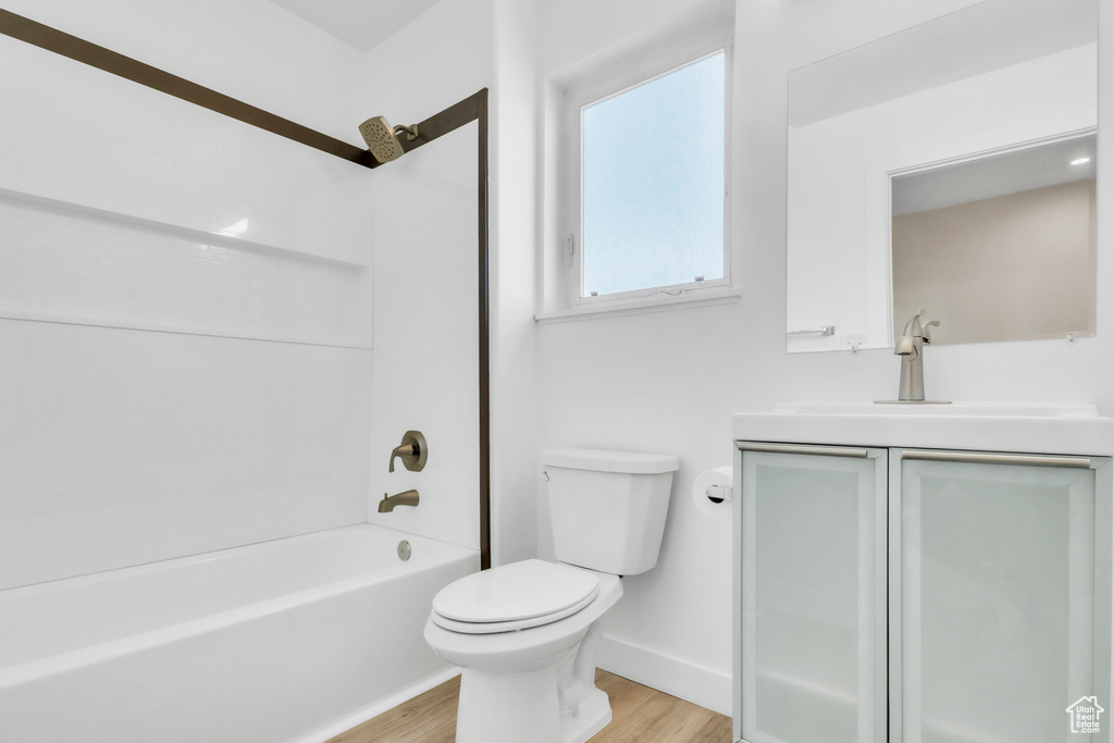 Full bathroom with wood finished floors, vanity, toilet, baseboards, and bathing tub / shower combination
