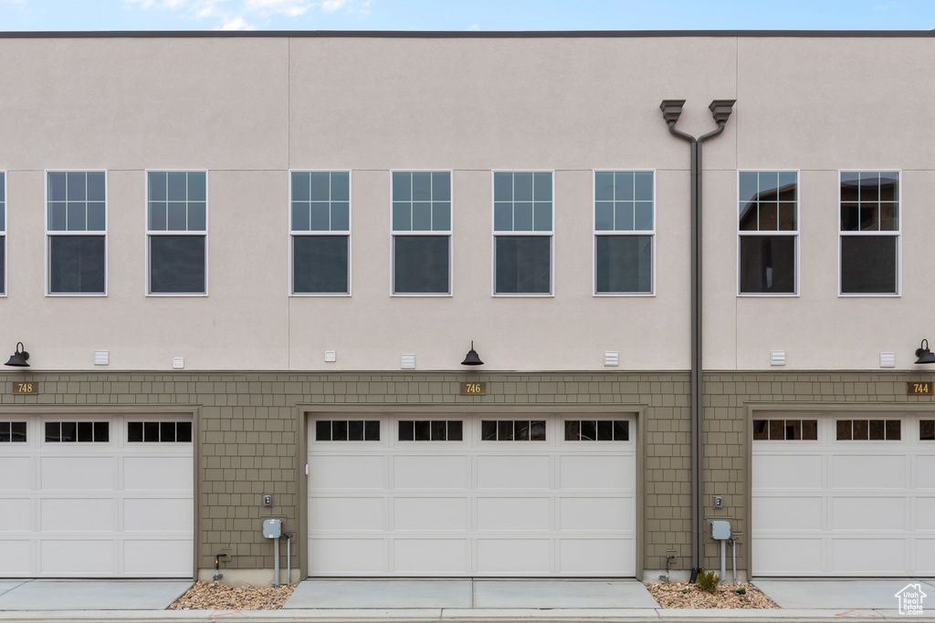 View of front of property with stucco siding, an attached garage, and driveway