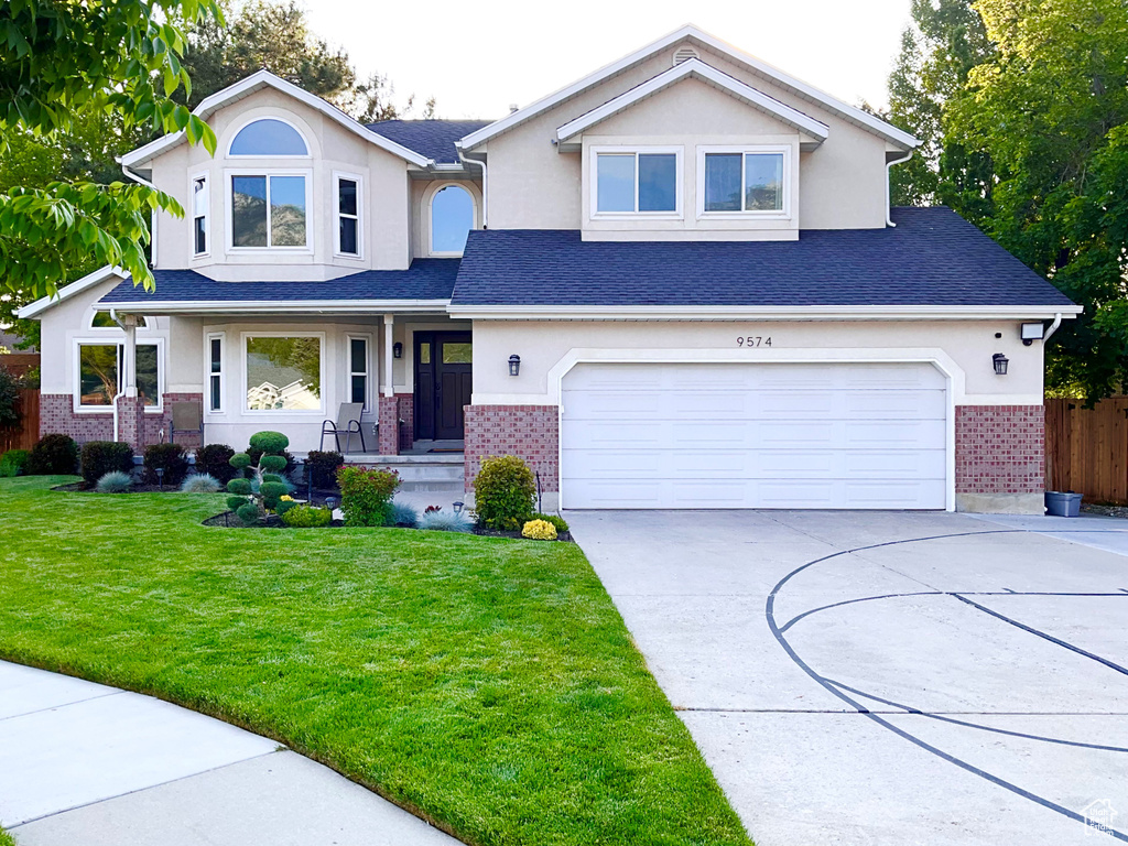 View of front of property featuring brick siding, concrete driveway, a garage, and stucco siding