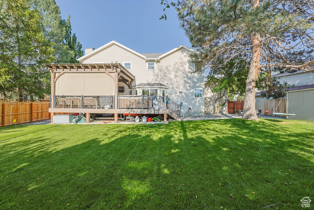 Rear view of house featuring a deck, stucco siding, and a chimney