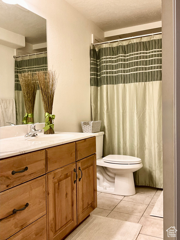 Full bath with vanity, toilet, tile patterned floors, and a textured ceiling