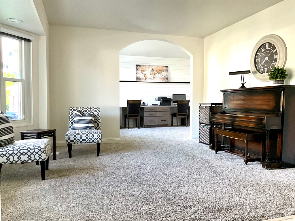 Sitting room with carpet floors, an office area, baseboards, and arched walkways