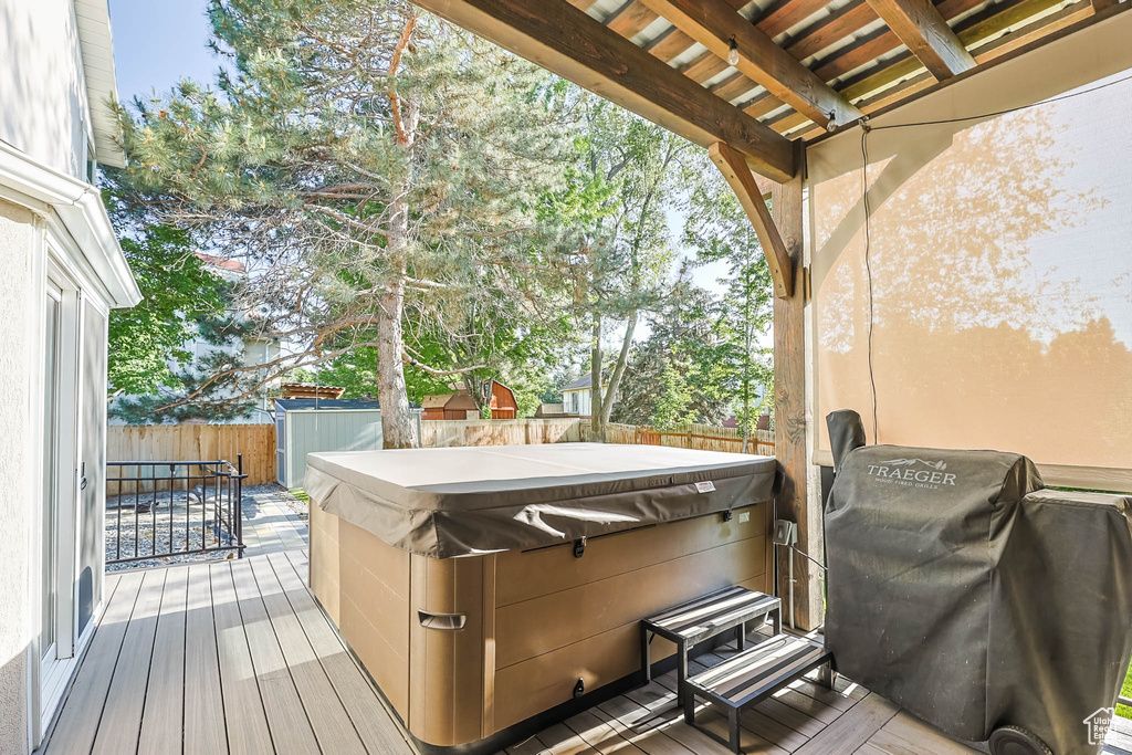 Wooden terrace featuring a hot tub, a fenced backyard, and a grill