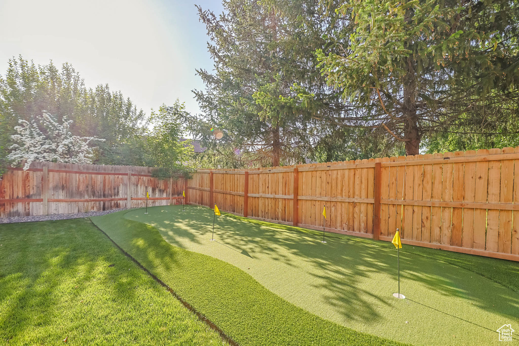 Fenced backyard featuring a putting area