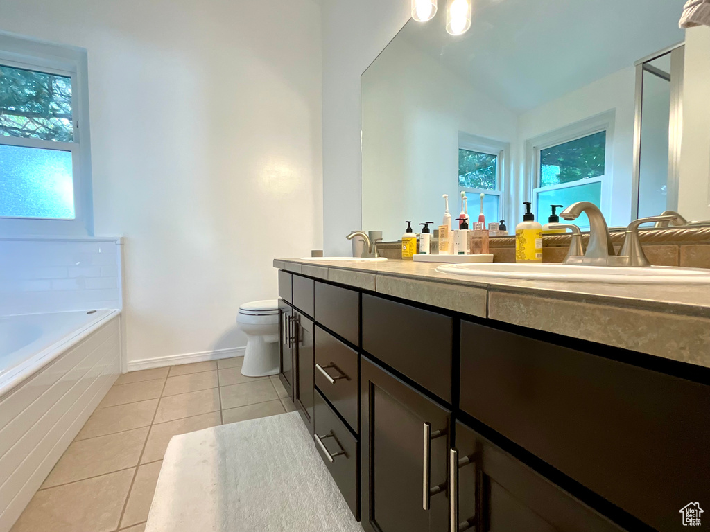 Full bathroom featuring double vanity, toilet, tile patterned flooring, and a bath