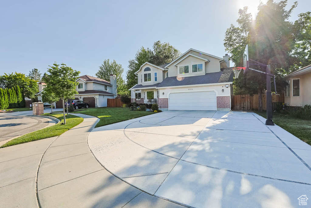 Traditional home with driveway, an attached garage, and brick siding
