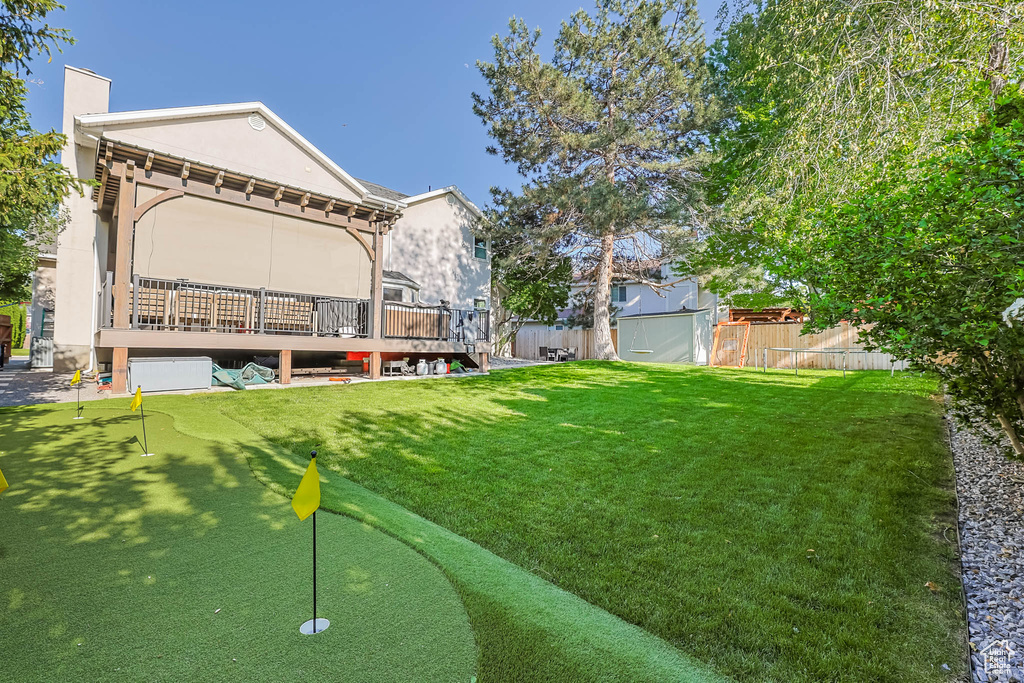 View of yard with an area to practice putting and a wooden deck