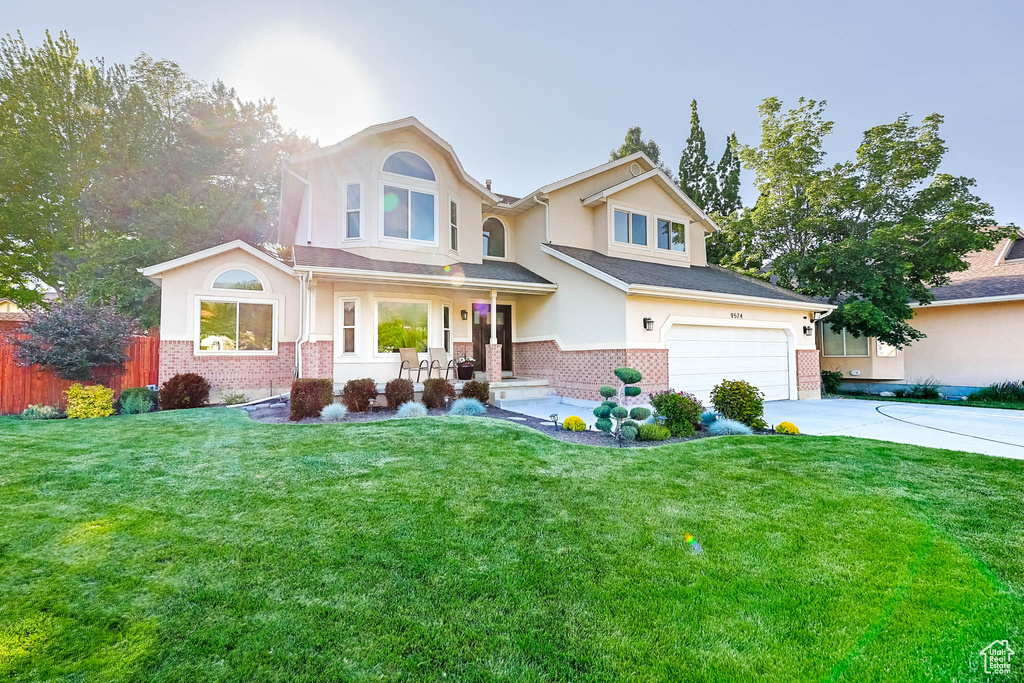 Traditional-style house with brick siding, concrete driveway, an attached garage, and stucco siding