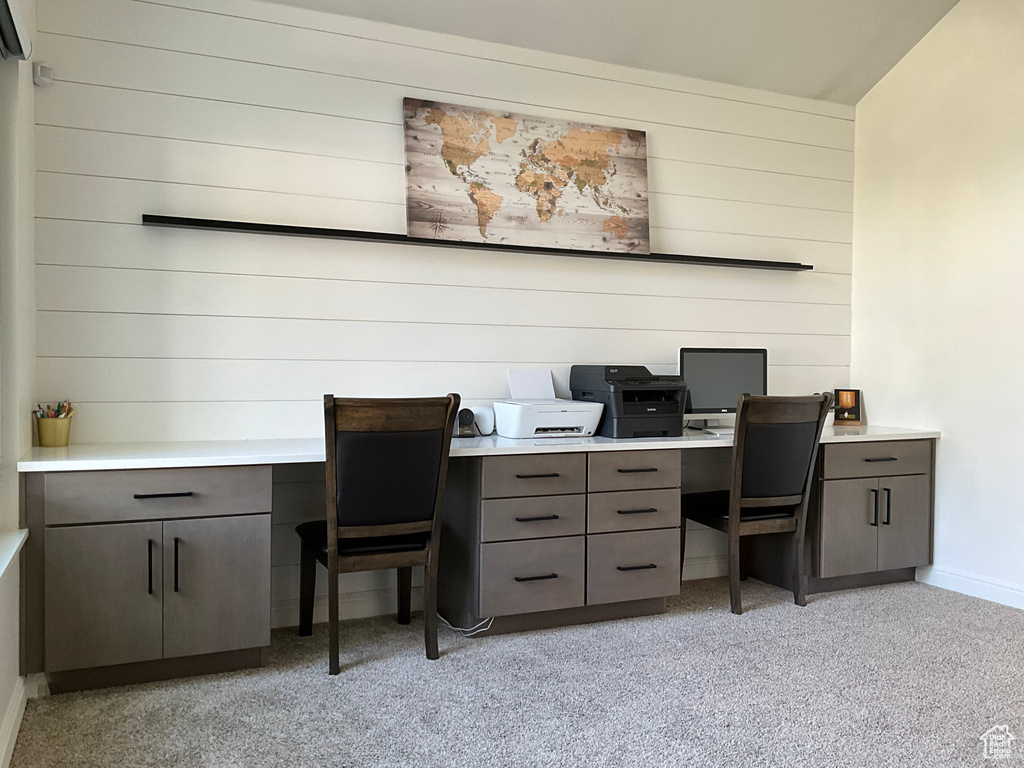 Office area featuring baseboards, wood walls, and built in desk