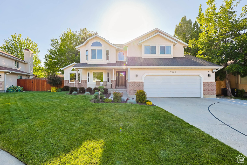 View of front of home with driveway, brick siding, an attached garage, and stucco siding
