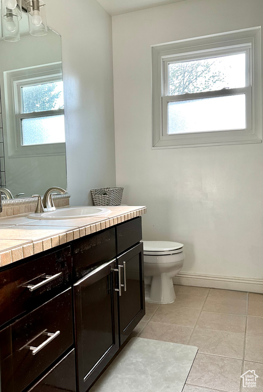 Bathroom with vanity, toilet, tile patterned flooring, and baseboards
