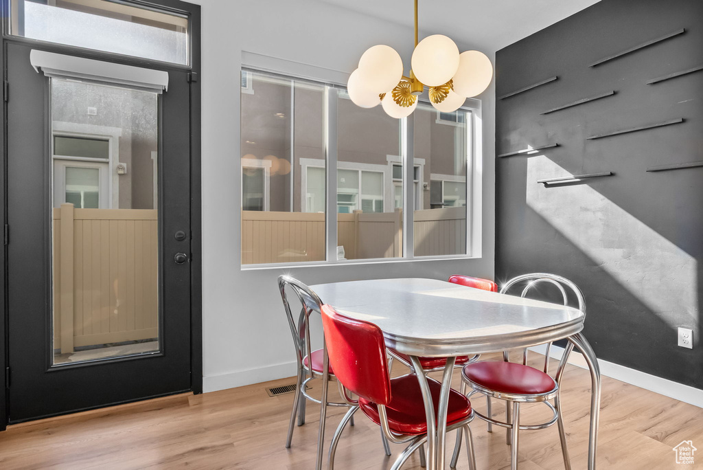 Dining room with a chandelier, wood finished floors, and baseboards