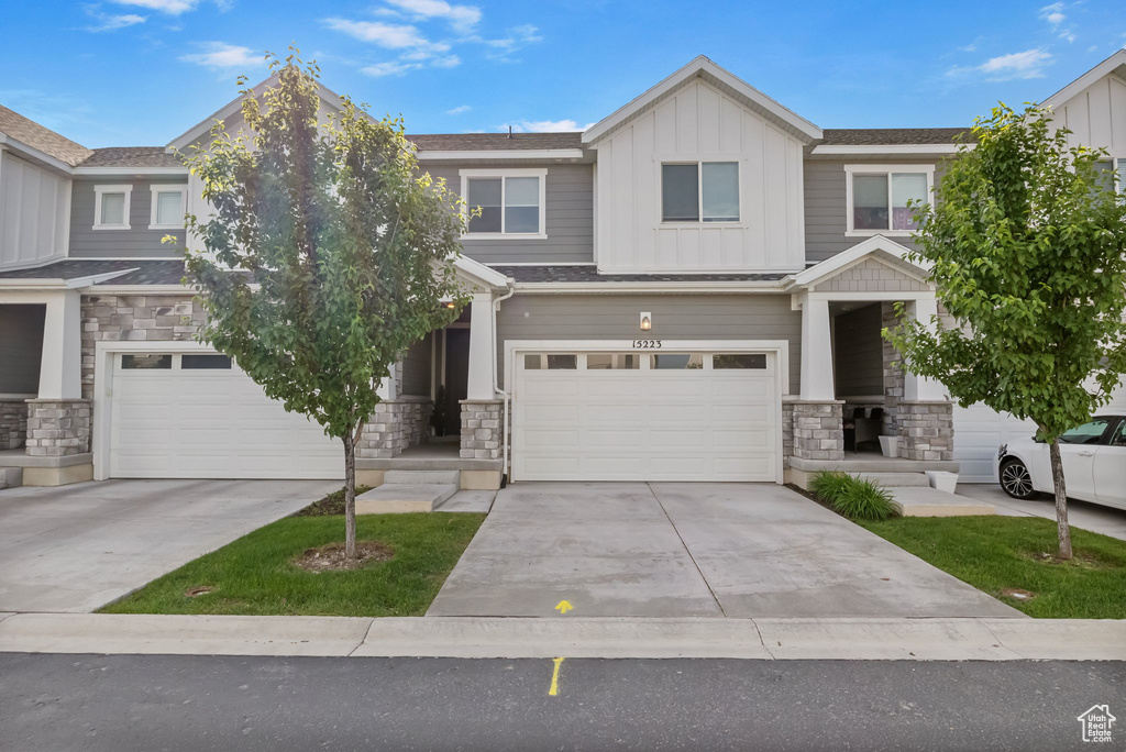 Craftsman house featuring stone siding, board and batten siding, a garage, and concrete driveway