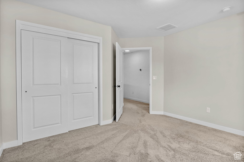 Unfurnished bedroom with carpet, a closet, and baseboards