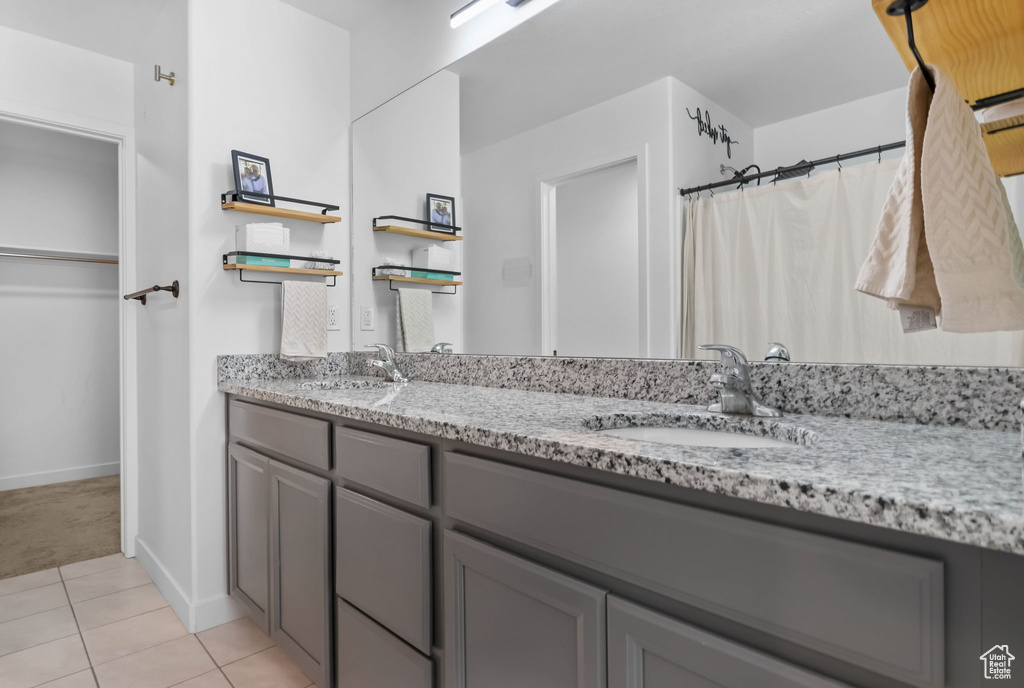 Bathroom with double vanity, tile patterned flooring, baseboards, and a shower with curtain