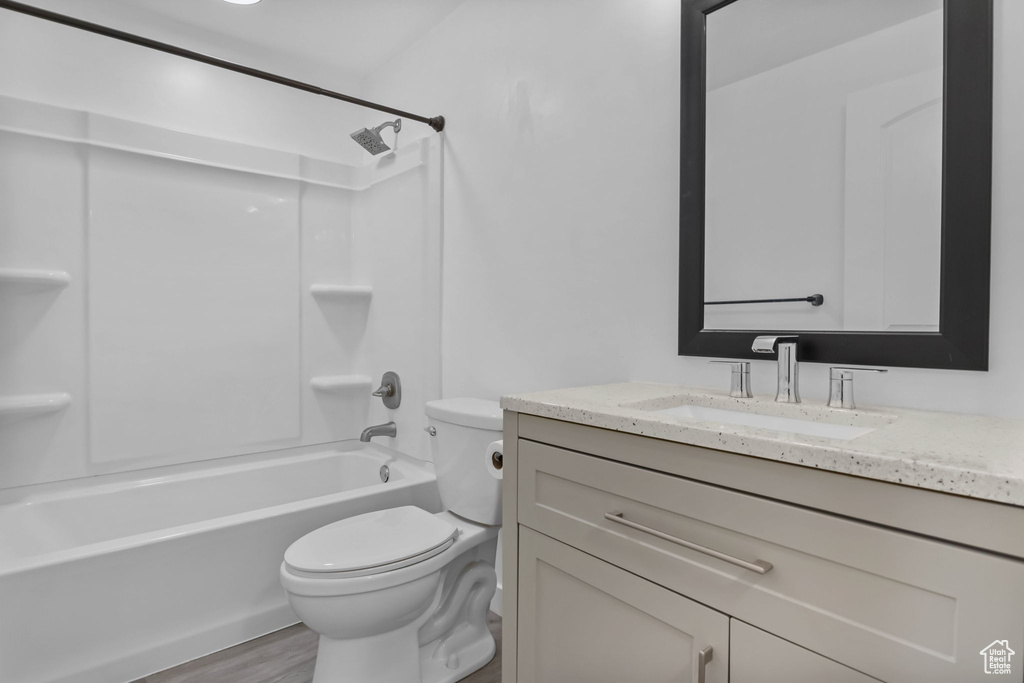 Bathroom featuring toilet, vanity, bathing tub / shower combination, and wood finished floors