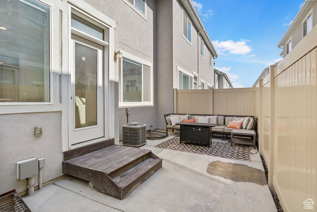 Fenced backyard with an outdoor living space, a patio area, and central AC unit