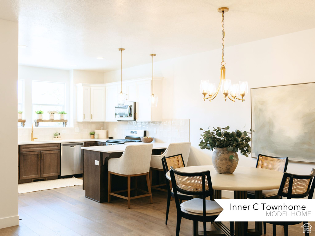 Dining space with light wood-style floors, a chandelier, and recessed lighting