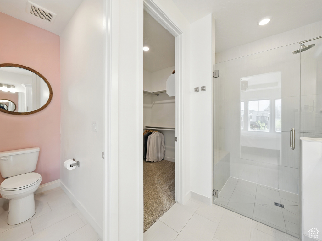 Bathroom with a shower stall, tile patterned floors, baseboards, a walk in closet, and recessed lighting