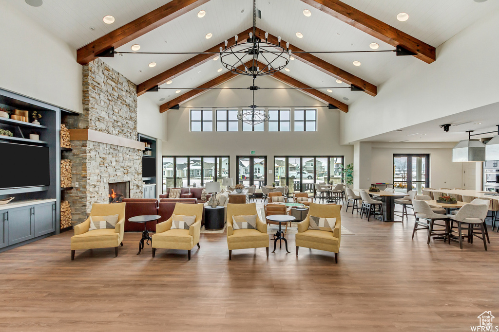 Living room with high vaulted ceiling, beamed ceiling, a stone fireplace, wood finished floors, and recessed lighting