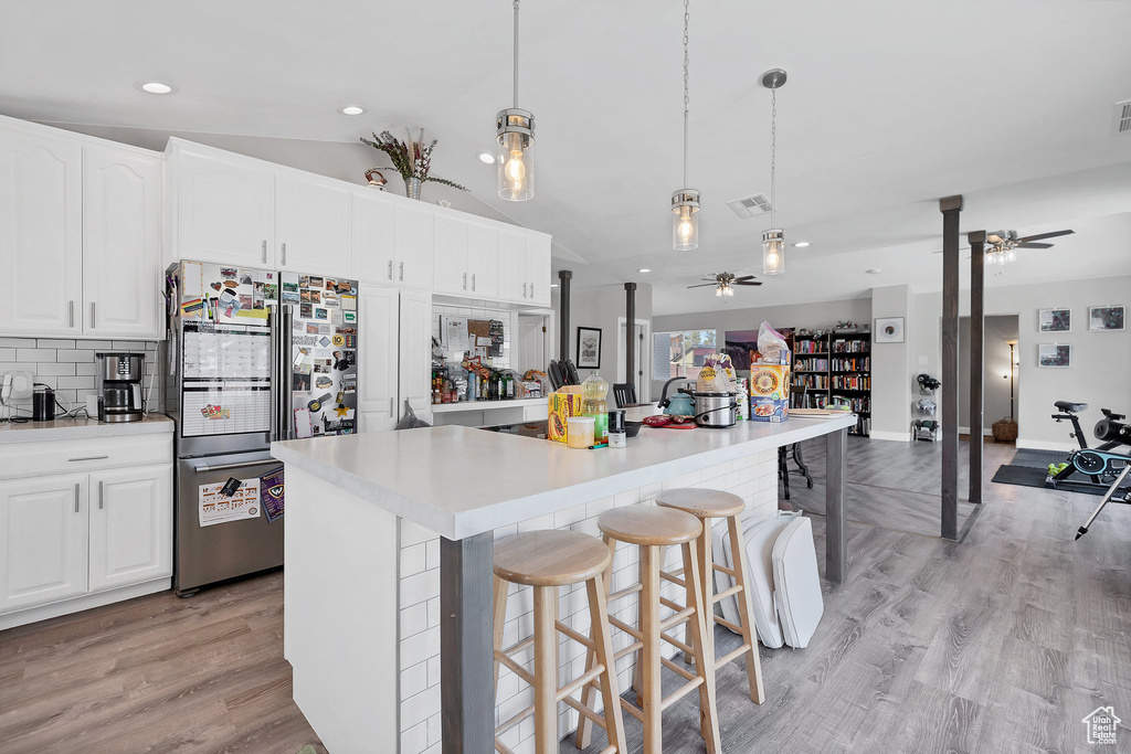 Kitchen featuring freestanding refrigerator, ceiling fan, white cabinets, a large island, and pendant lighting