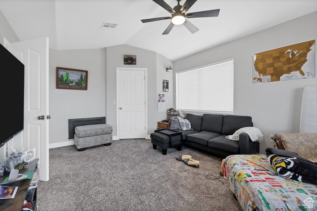 Carpeted living area with vaulted ceiling, a ceiling fan, and baseboards