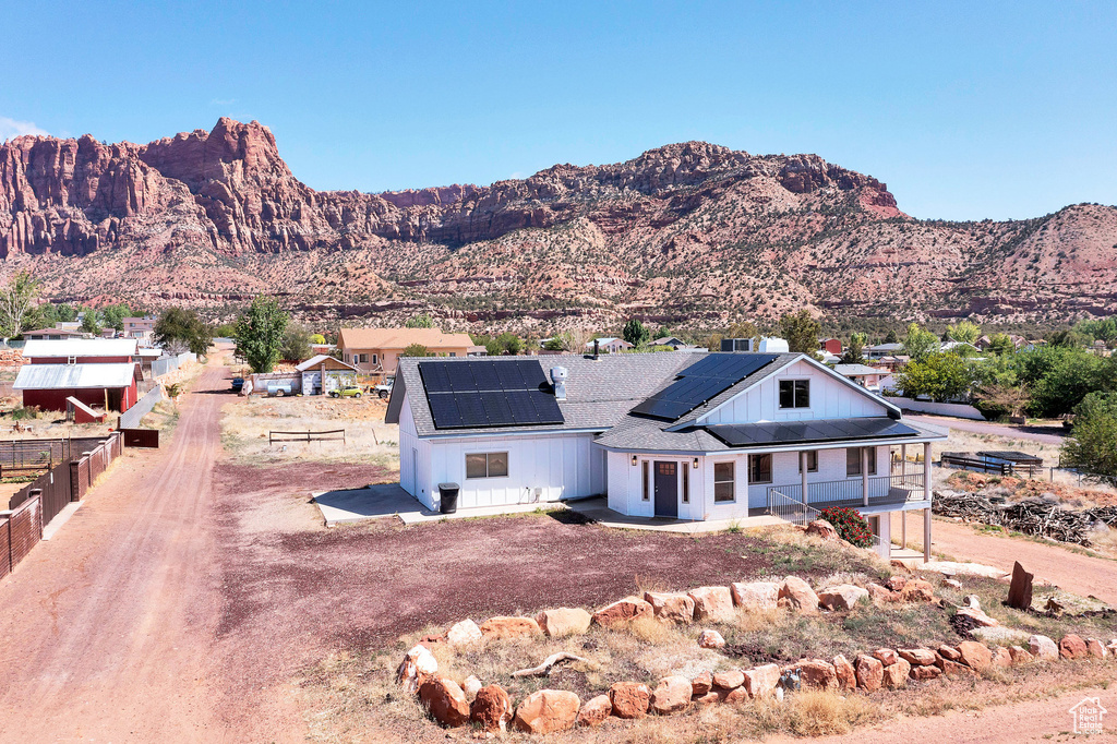 View of front of property with a porch, roof mounted solar panels, and a mountain view