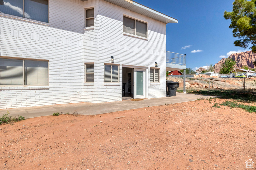 Rear view of house featuring brick siding and a patio area