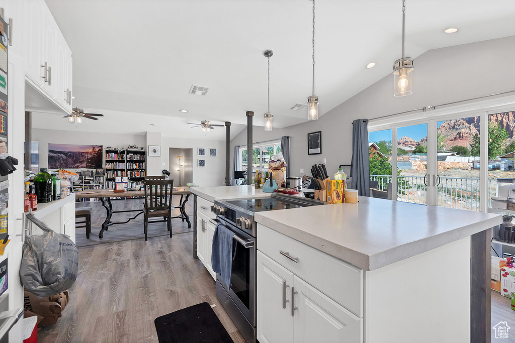 Kitchen with electric range, vaulted ceiling, ceiling fan, white cabinetry, and light countertops