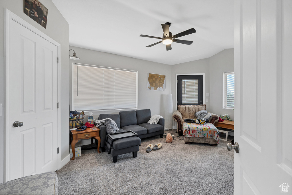 Living room featuring carpet and a ceiling fan