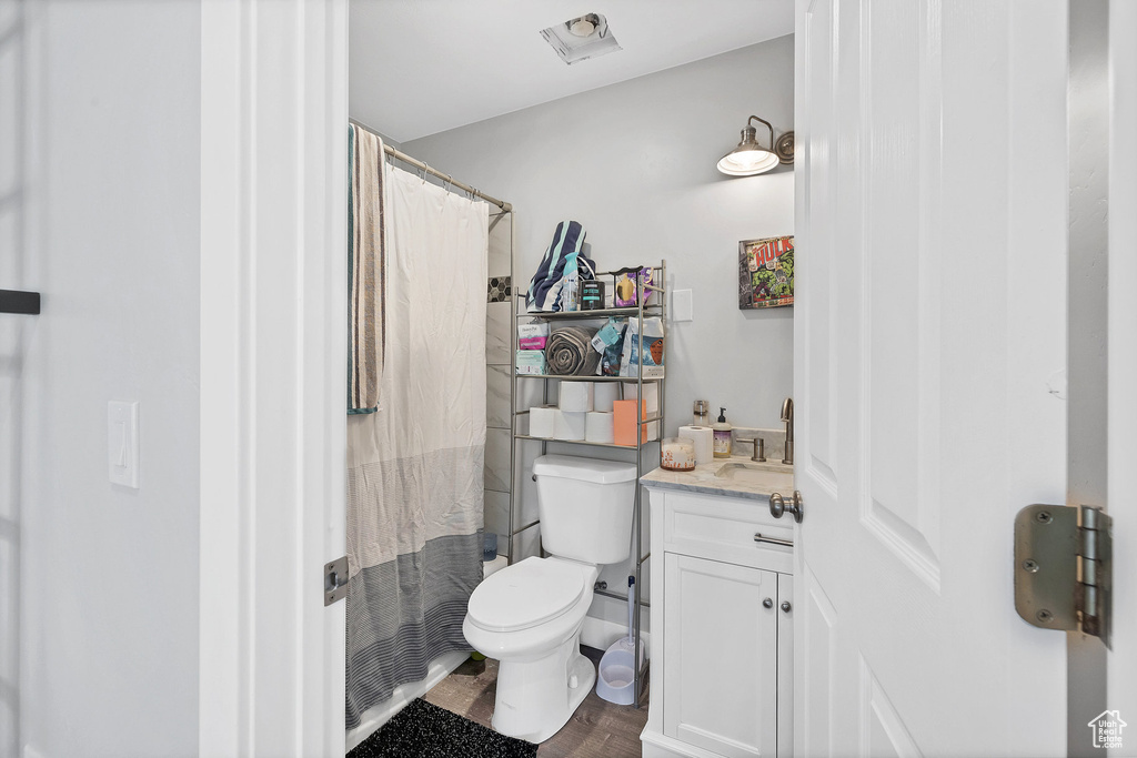 Bathroom featuring toilet, vanity, wood finished floors, and curtained shower