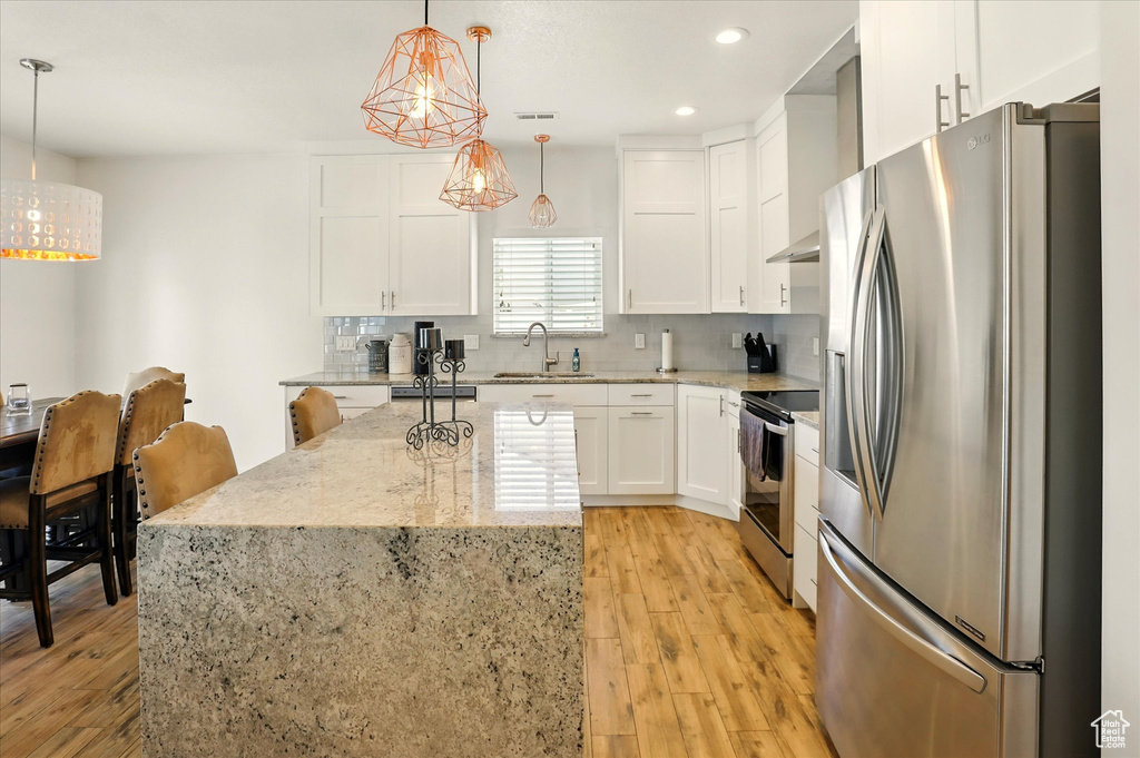 Kitchen with stainless steel appliances, a sink, light wood-type flooring, recessed lighting, and white cabinetry