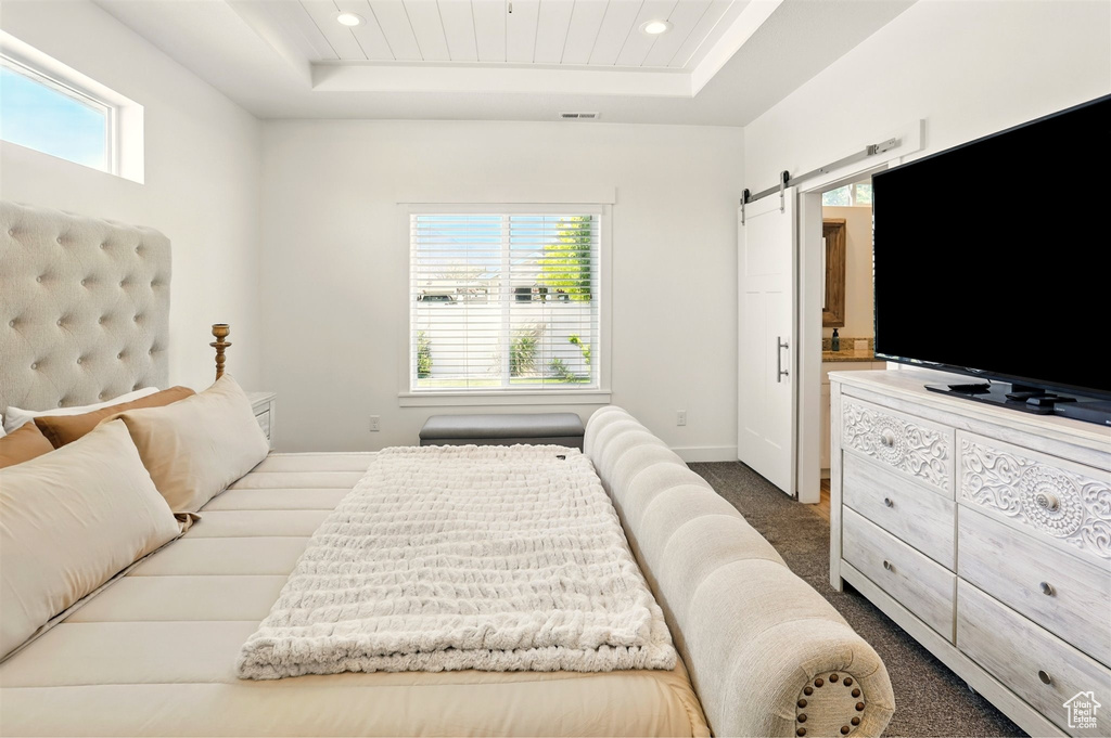 Bedroom featuring a raised ceiling, a barn door, carpet floors, recessed lighting, and baseboards