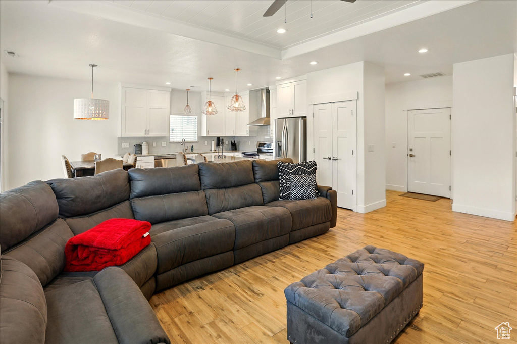 Living room featuring light wood finished floors, a ceiling fan, recessed lighting, and baseboards