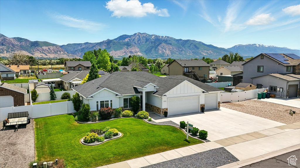View of front of house with board and batten siding, a residential view, a garage, a mountain view, and driveway