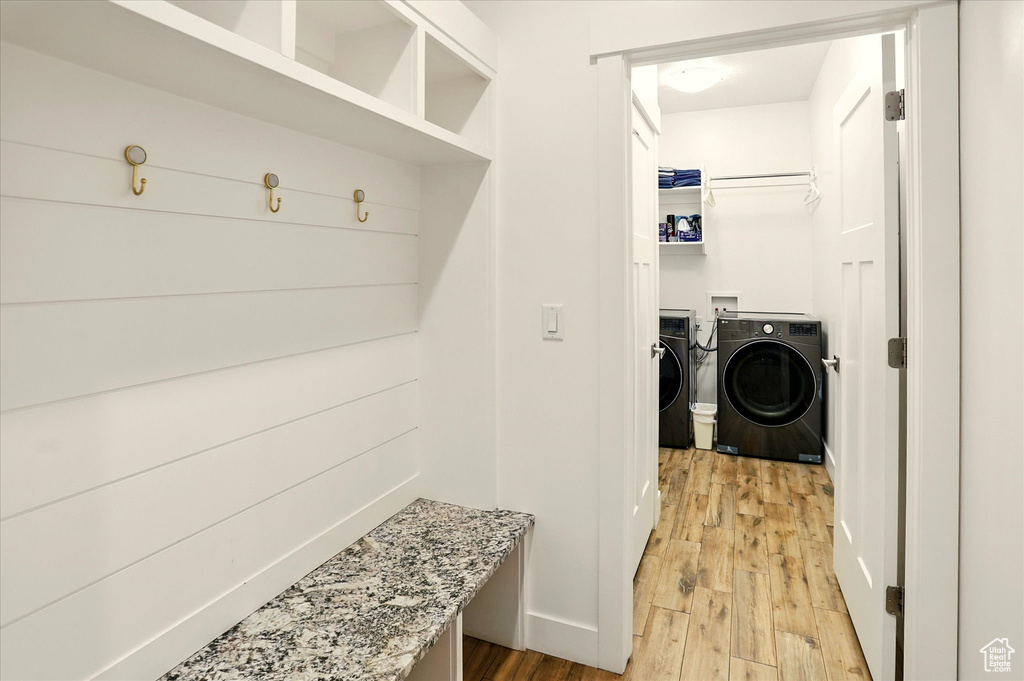 Mudroom featuring washing machine and clothes dryer, light wood-style floors, and baseboards