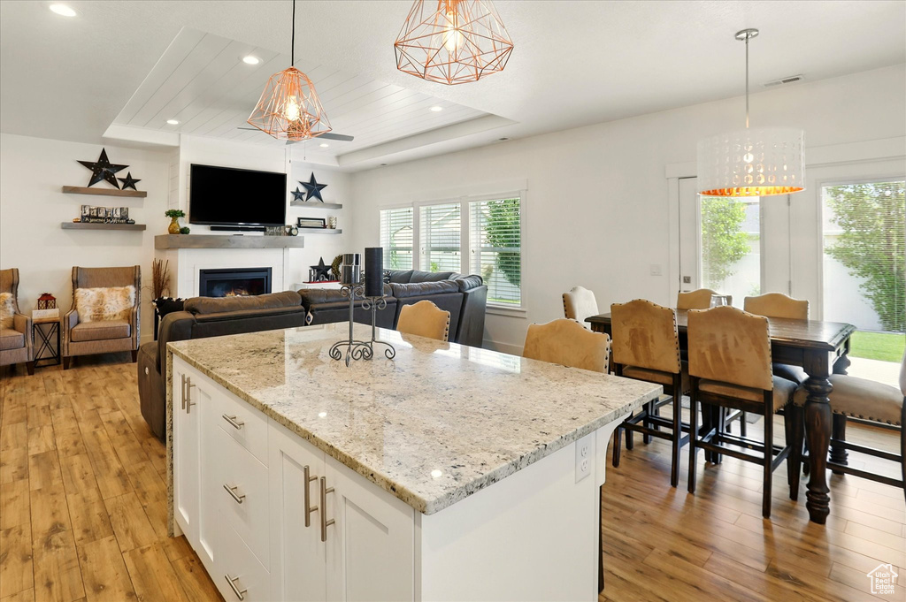 Kitchen featuring a raised ceiling, light wood-style floors, plenty of natural light, white cabinets, and recessed lighting