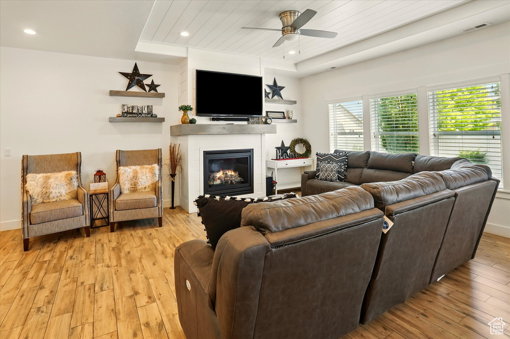 Living room with light wood finished floors, ceiling fan, a glass covered fireplace, recessed lighting, and baseboards