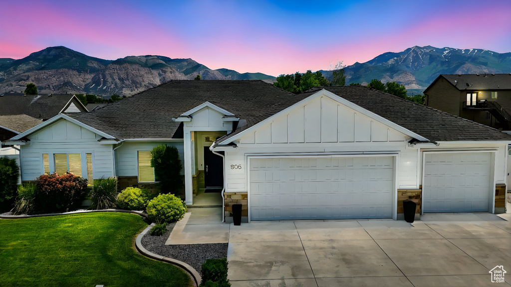 Ranch-style house with stone siding, board and batten siding, an attached garage, and driveway