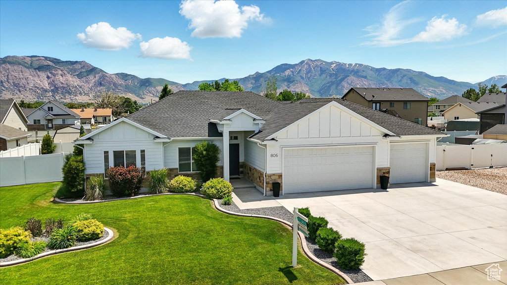 View of front of property with board and batten siding, stone siding, a garage, a mountain view, and driveway