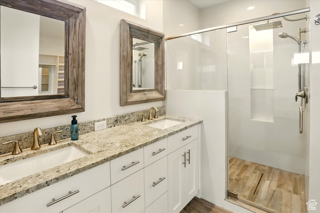 Bathroom featuring wood finished floors, a shower stall, and double vanity