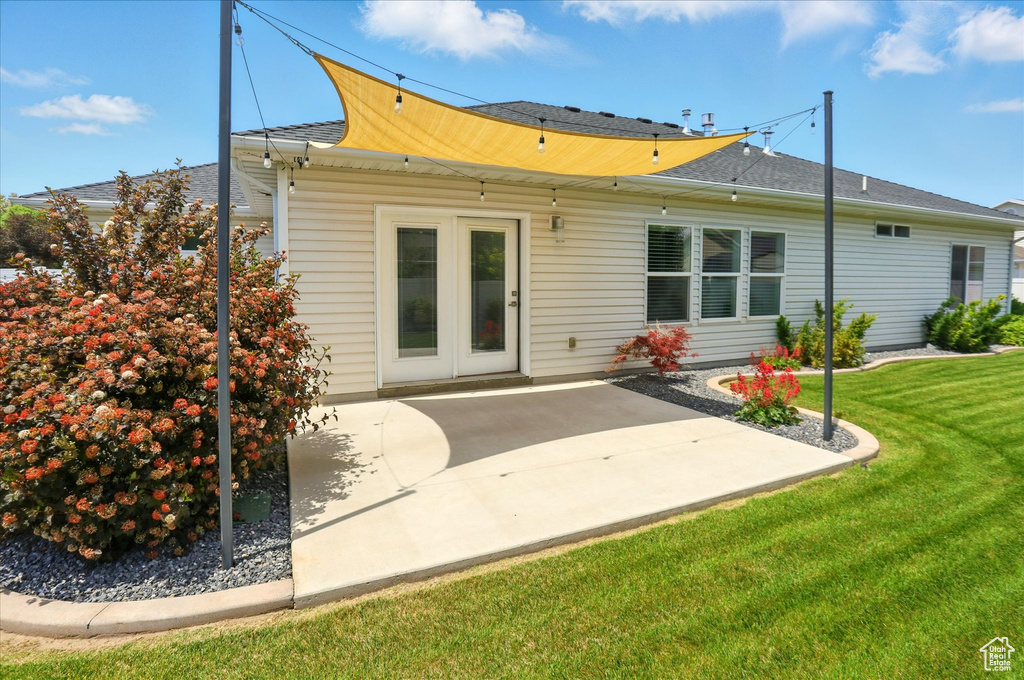 Back of house with a patio area, a yard, and roof with shingles