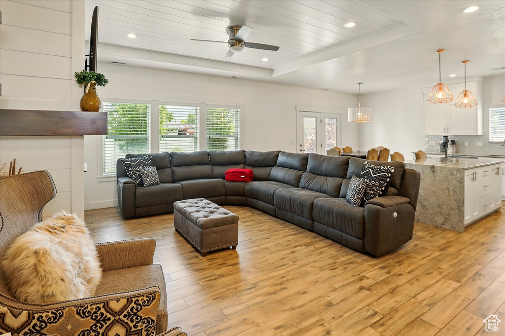 Living room featuring light wood-style flooring, plenty of natural light, a raised ceiling, and recessed lighting