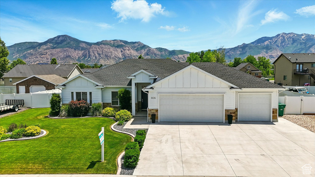 View of front of home featuring board and batten siding, a garage, stone siding, driveway, and a mountain view