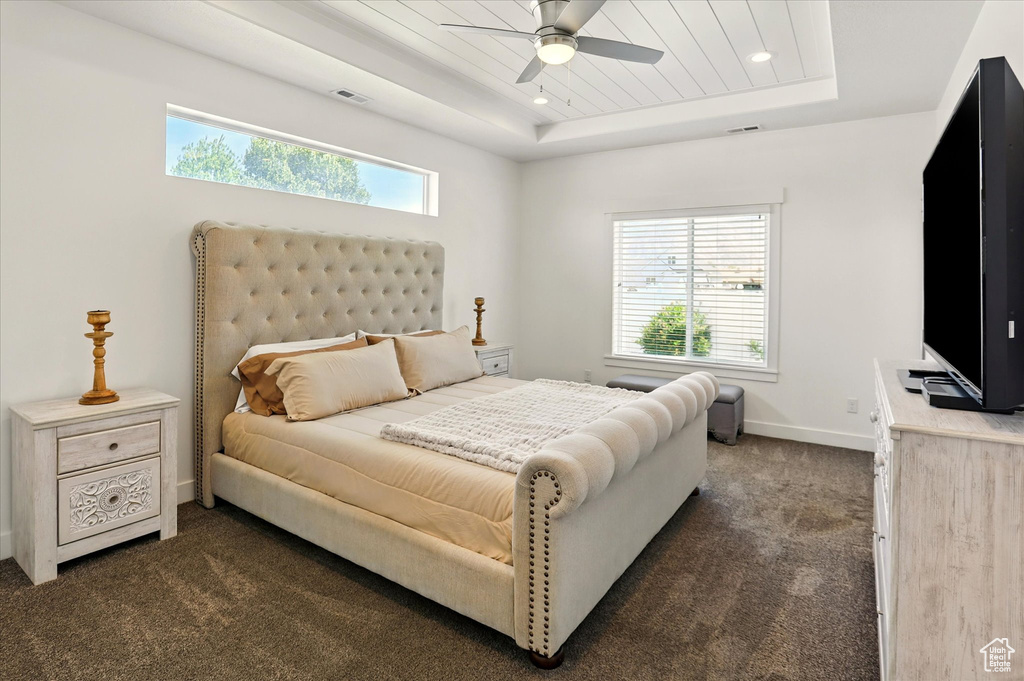 Bedroom with a tray ceiling, dark carpet, baseboards, recessed lighting, and a ceiling fan